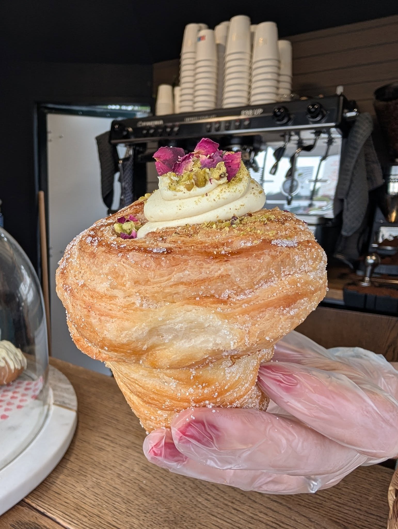 Sugared cruffin topped with pistachio cream and rose petals